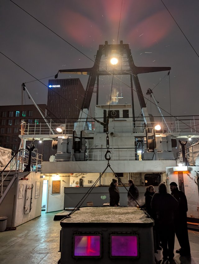 View of the ship's deck with a few people gathering around the entrance door, talking